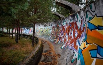 Znečištěný prostor s troskami, nečistotami a zdobený graffiti. V blízkosti olympijské vesnice se nachází oblast určená pro migranty.